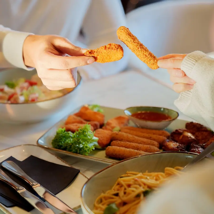 Zwei Personen teilen Fingerfood an einem gedeckten Tisch im The Leaf