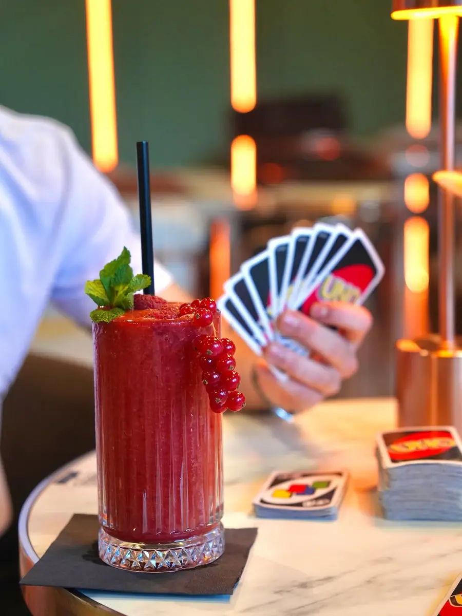 UNO-Karten und roter Fruchtdrink auf einem Tisch im The Leaf