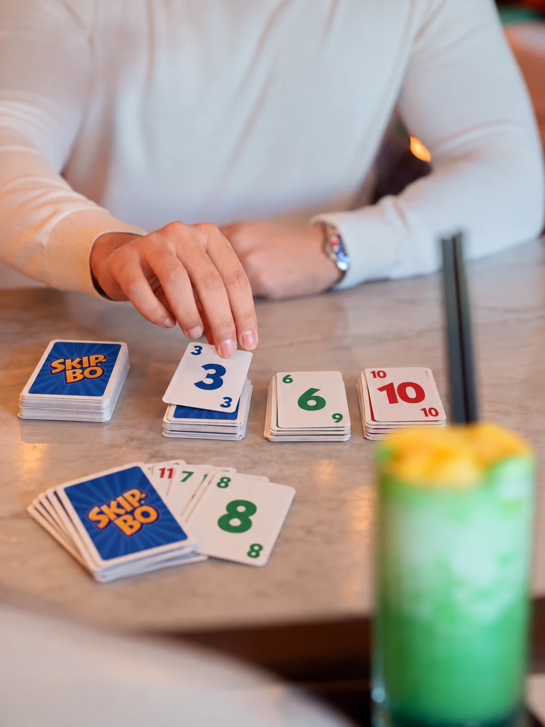 Skip-Bo-Karten auf einem Tisch, während eine Karte abgelegt wird